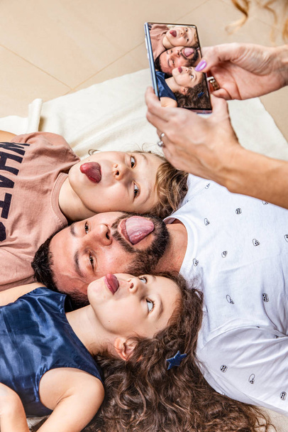 Moeder fotografeert haar familie op een smartphone - Foto, afbeelding
