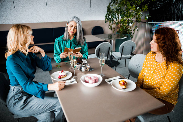 Три красивые женщины сидят за столом в кафе
 - Фото, изображение