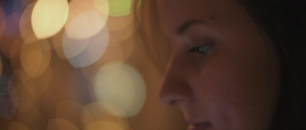 Lähikuva nuoren naisen kasvoista katsomassa hänen puhelintaan, yökaupungin bokeh-valot taustalla. Matala dof, reaaliaikainen, BMPCC 4K
 - Materiaali, video