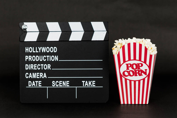 Clapboard e classica scatola di popcorn su sfondo nero
 - Foto, immagini