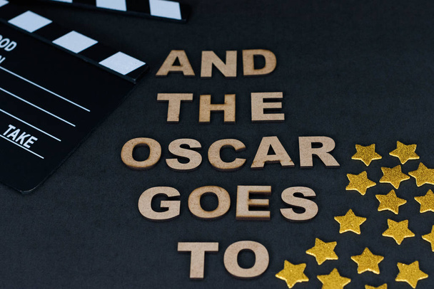 "Ja Oscar menee "valmistettu puisista kirjaimista, liitutaulu ja kultaiset tähdet mustalla pohjalla
 - Valokuva, kuva