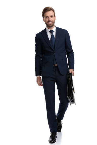 сексуальный молодой бизнесмен в темно-синем костюме с чемоданом и сантиметром
 - Фото, изображение
