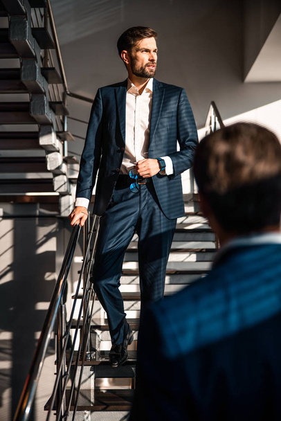Handsome young Caucasian businessman descending the staircase - Foto, Imagem