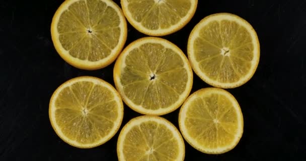 Collection of fresh orange slices on black background. Rotation citrus fruit. Top view. - Video