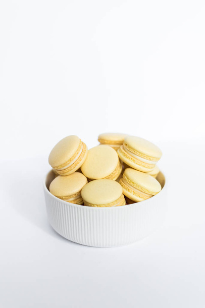 Yellow macaron in a white plate on a white isolated background - Foto, imagen