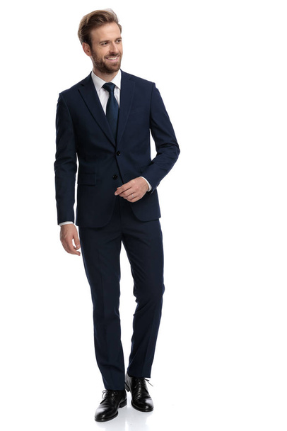 happy businessman in navy blue suit smiling and looking to side - Foto, imagen