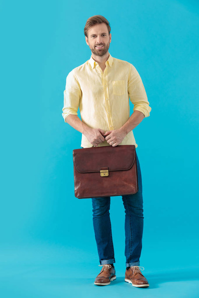 Confident casual man smiling and holding a briefcase - Foto, imagen