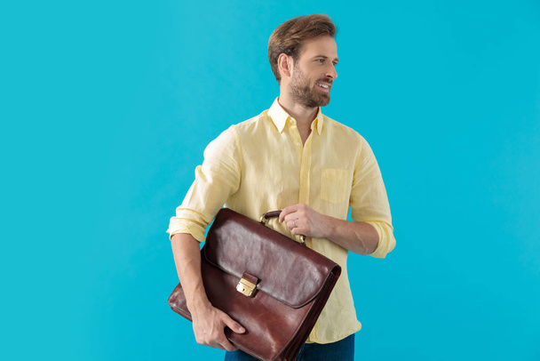 Pozitivní ležérní muž drží kufr a usmívá se - Fotografie, Obrázek