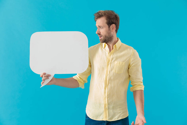 Shocked casual man holding a speech bubble and looking surprised - Photo, Image