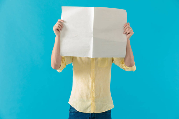 Junger Mann versteckt sein Gesicht hinter einer Zeitung - Foto, Bild