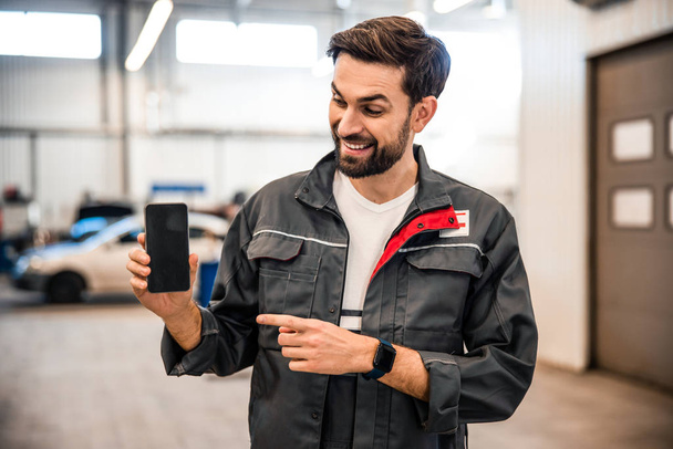 Mechanic holding a smartphone in his hand - Photo, image