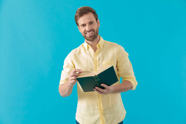 Θετική περιστασιακή άνθρωπος κρατώντας ένα βιβλίο και γελώντας - Φωτογραφία, εικόνα