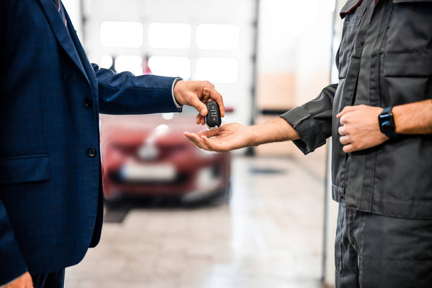 Worker receiving a car key fob from a businessman - Foto, afbeelding