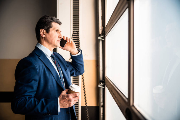Man with a smartphone standing in the corridor - Valokuva, kuva