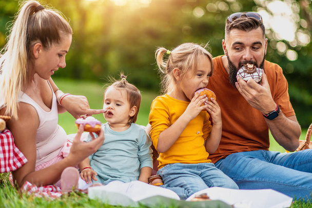 Joyful family picnicking in summer park - Photo, Image