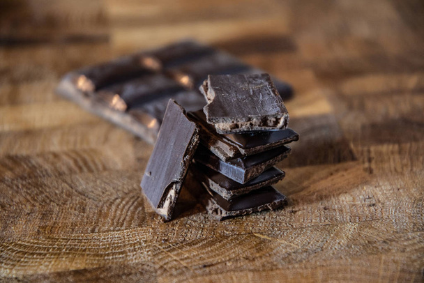 Black chocolate with truffle filling on a kitchen wooden board. - Valokuva, kuva