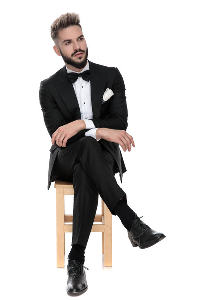 бизнесмен, сидящий со сложенными руками и ногами, отворачиваясь
 - Фото, изображение