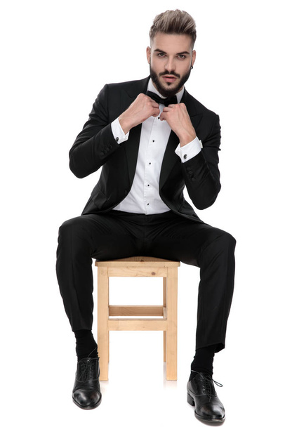 businessman sitting and fixing bowtie with class - Photo, Image