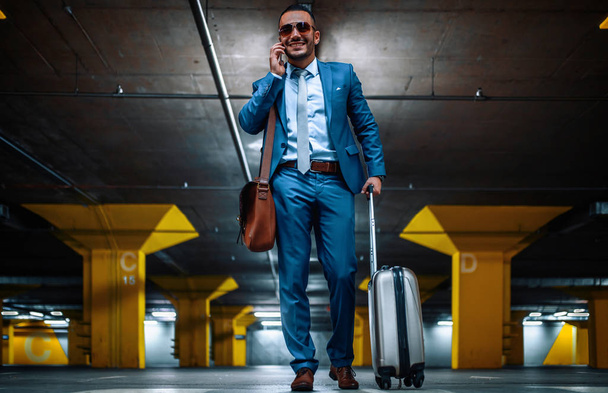 Businessman with suitcase in hall of airport - Foto, imagen