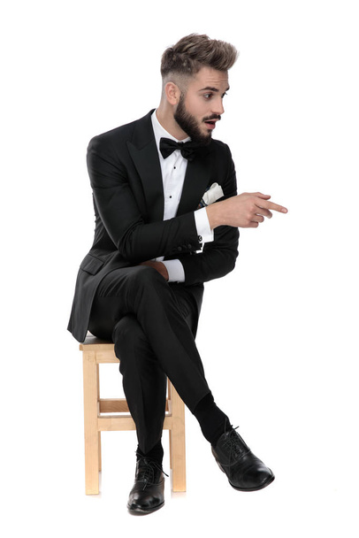 businessman sitting and pointing to a side shocked - Photo, Image