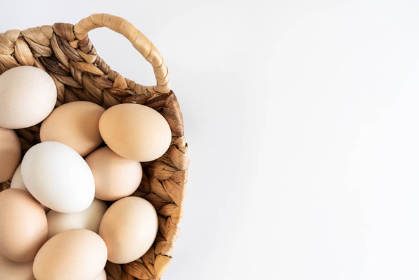 Huevos frescos crudos de chiken ecológico de granja en una canasta sobre fondo blanco
. - Foto, Imagen