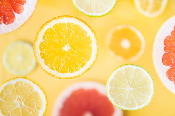 Variedad de cítricos en rodajas de fruta levitando por encima del fondo amarillo
 - Foto, Imagen