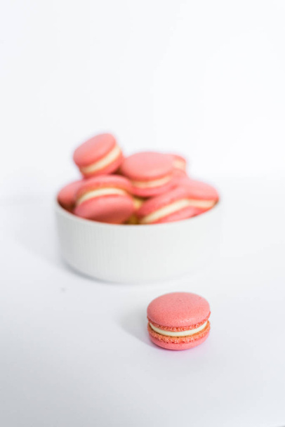 Pink macaron in a white plate on a white isolated background - Foto, Imagen
