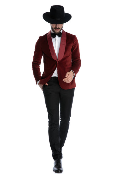 fashion young man in red velvet tuxedo walking and looking down - Fotoğraf, Görsel