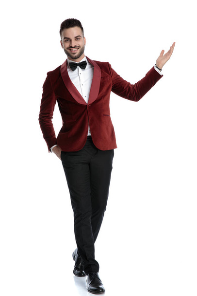 happy young model in tuxedo smiling and presenting to side - Photo, image