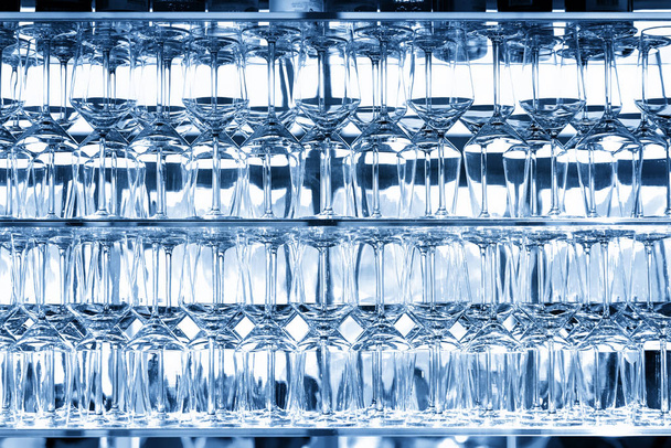 Monien tyhjien läpinäkyvien viinilasien seinä baarissa sijaitsevan kahvilan lasihyllyllä taustavalaistua ikkunaa vasten. Abstrakti alkoholijuomien pubi tausta. lähikuva yksityiskohtaisesti lasi kuvio. Klassinen sininen
 - Valokuva, kuva