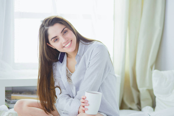 Woman sitting in bed reading a book and having breakfast - Photo, Image