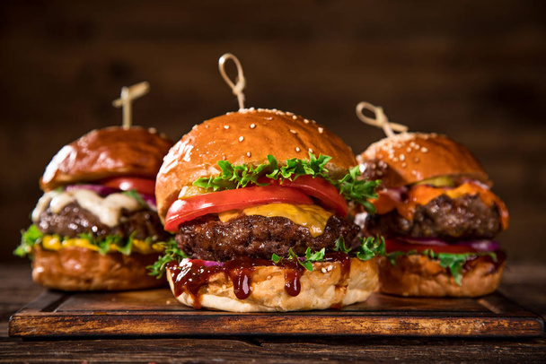 Tasty burgers on wooden table. - Fotoğraf, Görsel