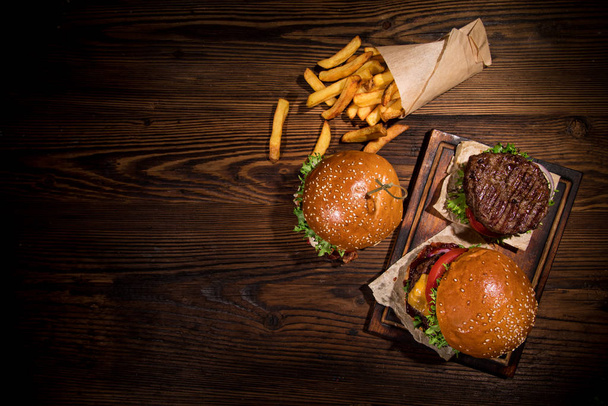 Top view of tasty burgers on wooden table. - Fotoğraf, Görsel