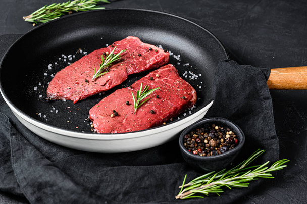Raw rump steak in a frying pan. Beef meat. Black background. Top view - Zdjęcie, obraz