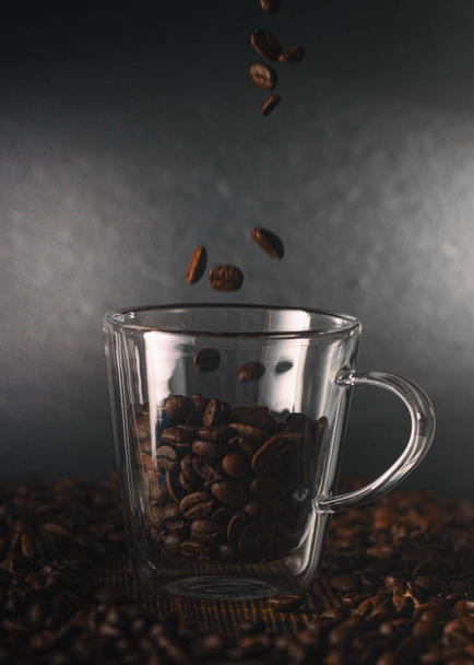 Fondo con semillas de café en taza de vidrio sobre mesa de madera
 - Foto, imagen