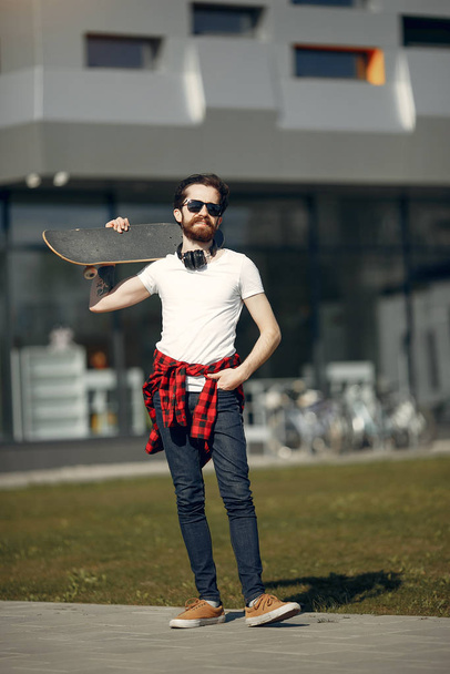 Stylish guy with skate in a summer city - Fotoğraf, Görsel