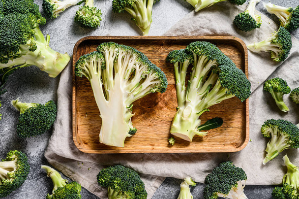 Raw broccoli halves in a wooden bowl. Gray background. Top view. - Foto, imagen