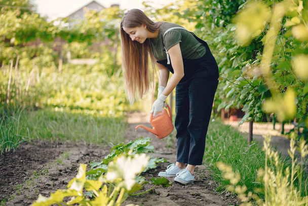 Gyönyörű nő dolgozik egy kertben, közel a házhoz - Fotó, kép