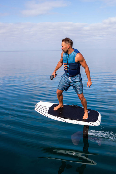 Uomo a bordo di un aliscafo elettrico su un lago con giubbotto salvagente
 - Foto, immagini