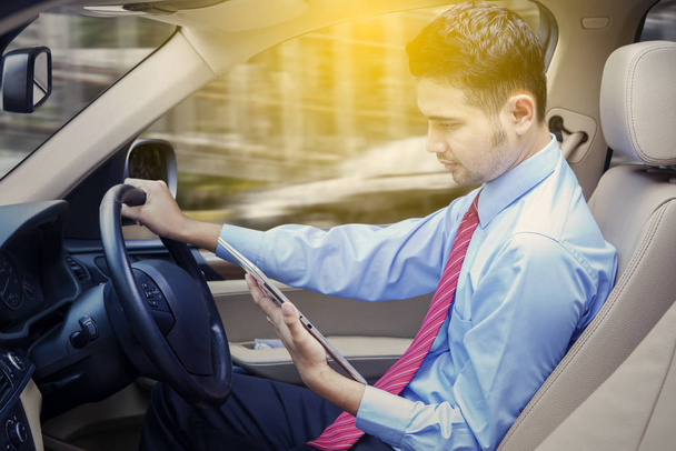 Businessman driving car while using tablet - Valokuva, kuva