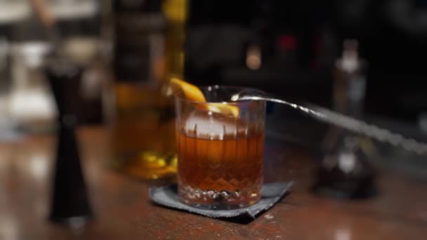Glas met sinaasappelschil en ijscocktail, slow motion, ondiepe scherptediepte. Focus transitie - Video