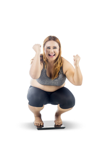 Obese woman squat down on the weight scales - Fotoğraf, Görsel