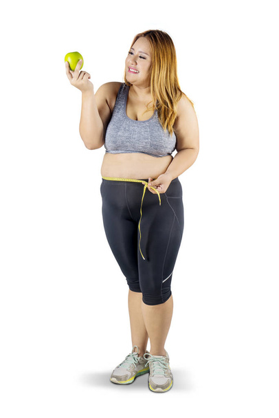 Obese woman with apple fruit and measuring tape - 写真・画像