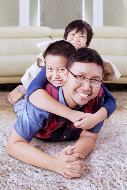 Kids cuddling on their fathers back in their home - Foto, Imagen