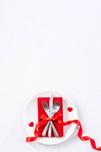 Valentine's Day, Mother's Day, holiday dating meal, banquet design concept - White plate and red ribbon on marble background, top view, flat lay. - Фото, зображення