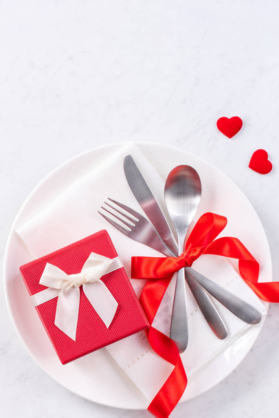 Valentine's Day, Mother's Day, holiday dating meal, banquet design concept - White plate and red ribbon on marble background, top view, flat lay. - Valokuva, kuva