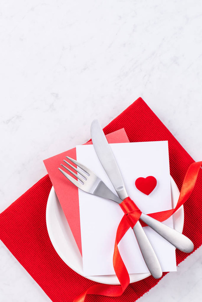 Valentine's Day, Mother's Day, holiday dating meal, banquet design concept - White plate and red ribbon on marble background, top view, flat lay. - Valokuva, kuva