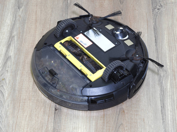 Cleaning the robot vacuum cleaner, robot vacuum cleaner service, servicing the working vacuum cleaner from long hair, which is wound on brushes  - Photo, Image