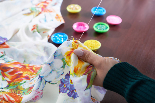 naaister kleermaker met behulp van kralen decoreren jurk in atelier - Foto, afbeelding