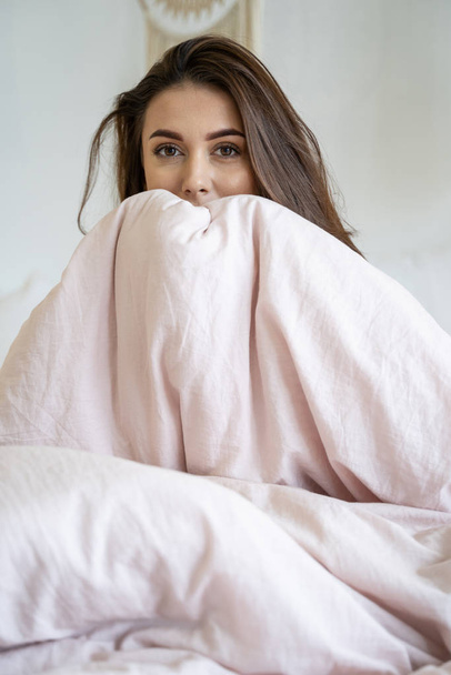 Young Caucasian woman sitting alone in bed - Foto, afbeelding